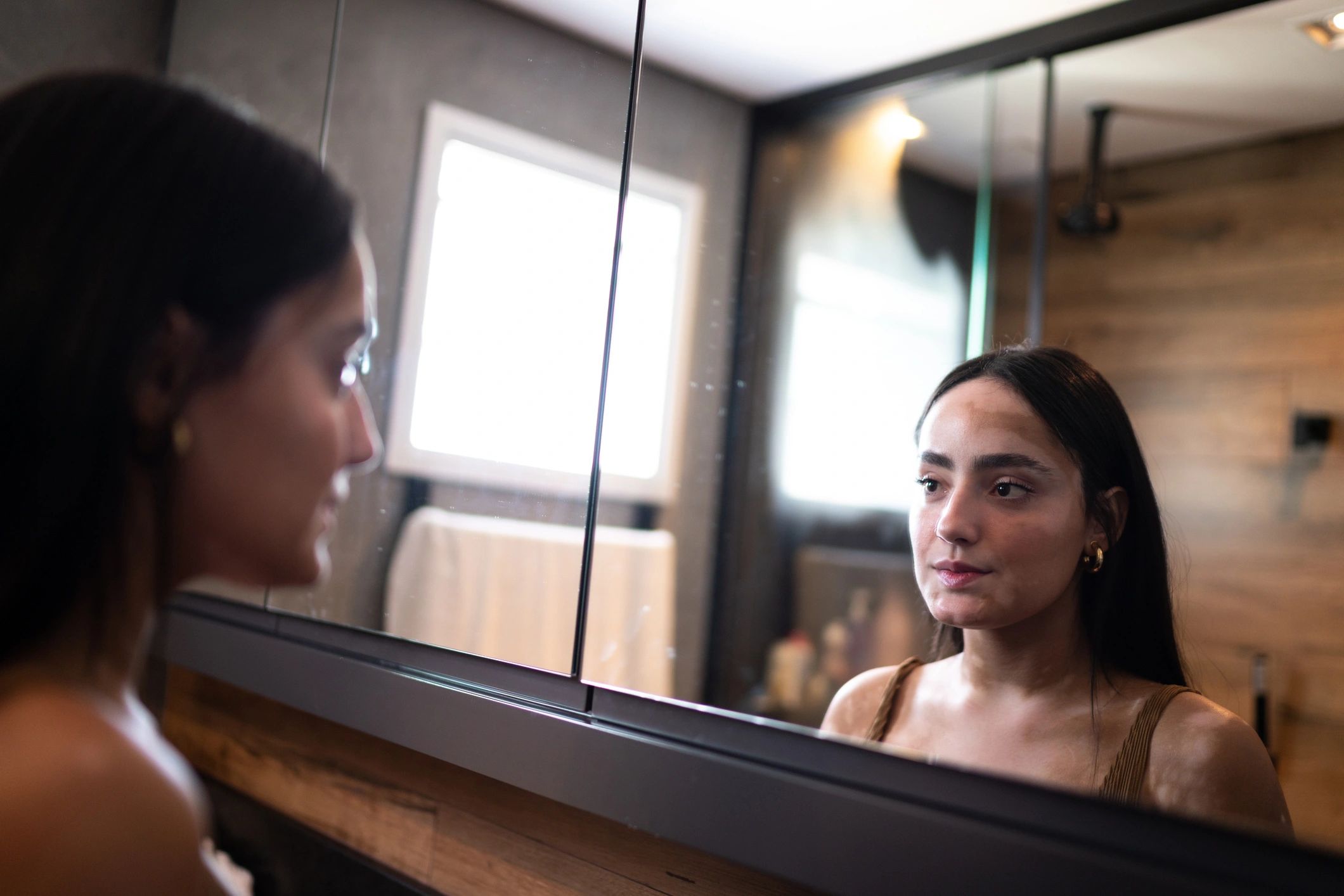 Woman looking in mirror during skincare routine